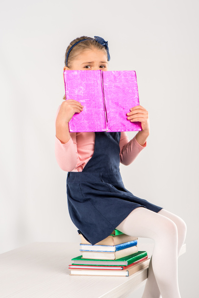 Schoolgirl sitting on pile of books - Valokuva, kuva