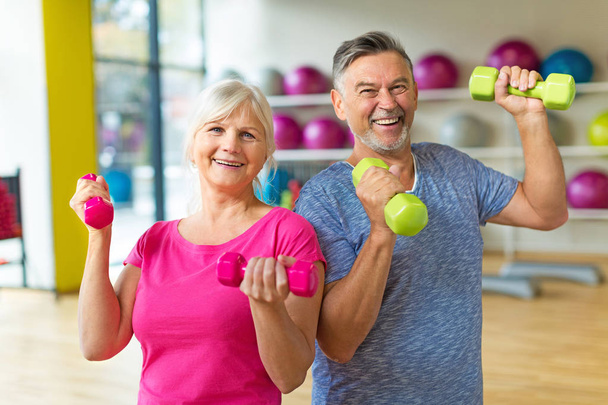 Senior couple exercising in gym - Фото, изображение