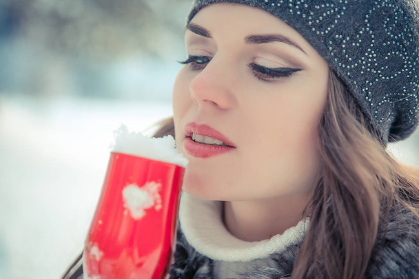 Portrait of a beautiful woman holding a glass of champagne with snow inside - Photo, Image