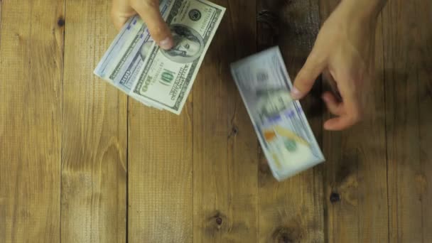 Les mains de l'homme considèrent les billets en dollars sur une table en bois
. - Séquence, vidéo