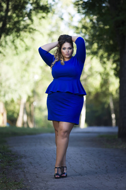 Young beautiful stylish plus size fashion model in blue dress outdoors, xxl woman on nature - Foto, afbeelding