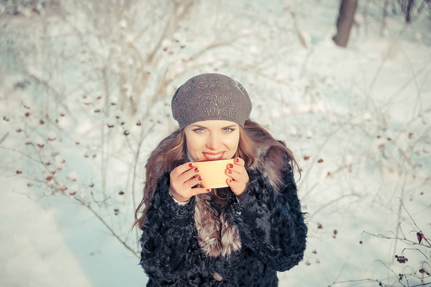 Mujer joven sosteniendo la taza con té al aire libre en invierno
 - Foto, imagen