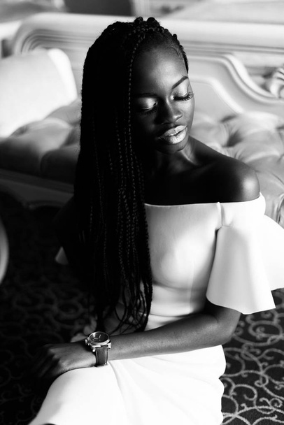 black and white photo of incredible african woman sitting on the floor in vip europian hotel. Hotel room with classic interior - Zdjęcie, obraz