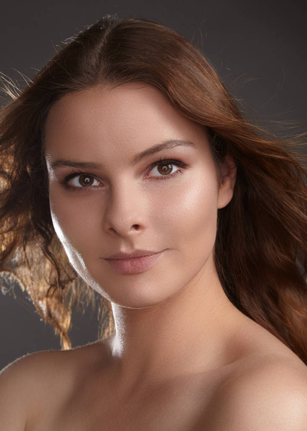 Beautiful young woman model with flying brown color hair. Beauty portrait with clean skin, glow glamour fashion makeup. Make up, curly hairstyle. Hair-care, make-up. Horizontal beauty portrait - Foto, Imagem