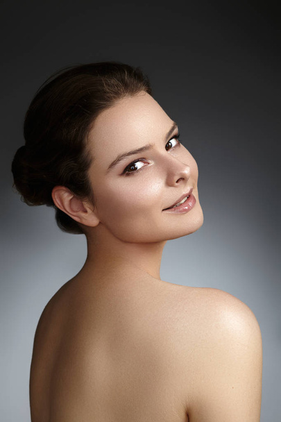 Beautiful young woman with clean face, shiny skin, fashion natural make-up, perfection eyebrows. Cute bun hairstyle. Spa portrait, naturel cosmetics, healthy fresh look - Foto, Bild