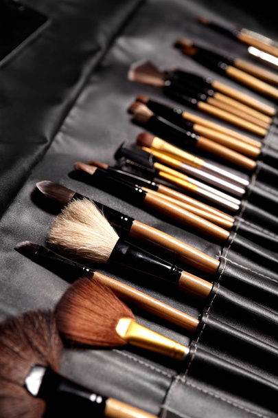 Set of make-up brushes in black makeup bag. Beauty tools for professional visage. Brushes for maskara, eyeshadows, foundation, lipstick, blush and facial cream - Photo, image