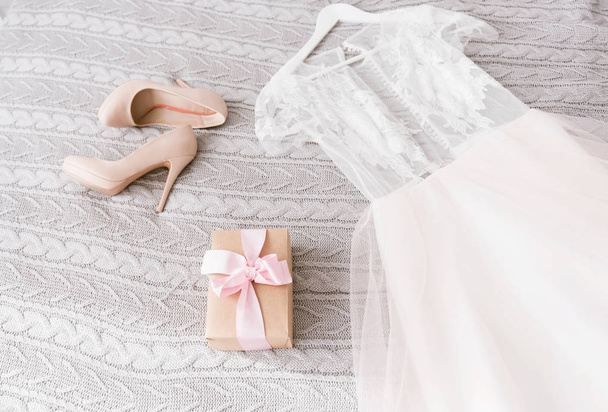 White wedding dress and shoes lying on the bed - Φωτογραφία, εικόνα