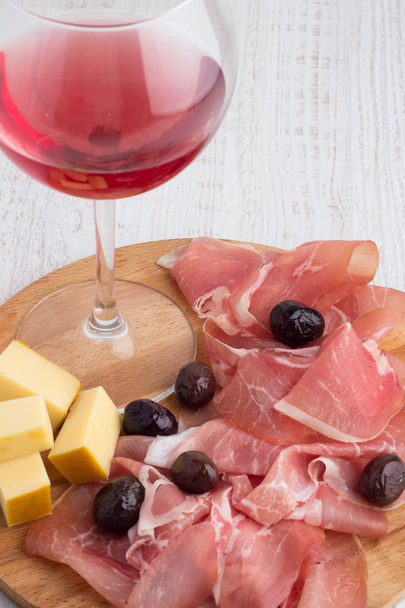 copa de vino, aceitunas y carne curada sobre un fondo blanco
 - Foto, Imagen