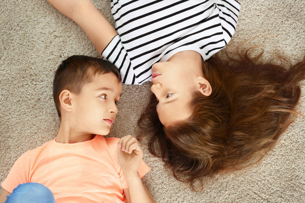 Brother and sister lying on carpet - Photo, Image