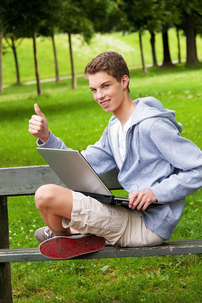 Teenager with laptop outdoors - 写真・画像