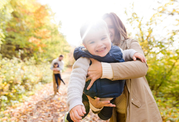 Beautiful young family on a walk in autumn forest. - 写真・画像