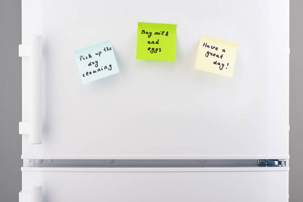 Reminder notes on blue, green and yellow paper on refrigerator  - Φωτογραφία, εικόνα