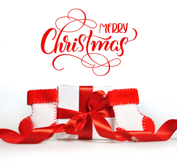 hermosas cajas de regalo con cintas rojas rama de árbol y texto Feliz Navidad. Letras de caligrafía
 - Foto, Imagen