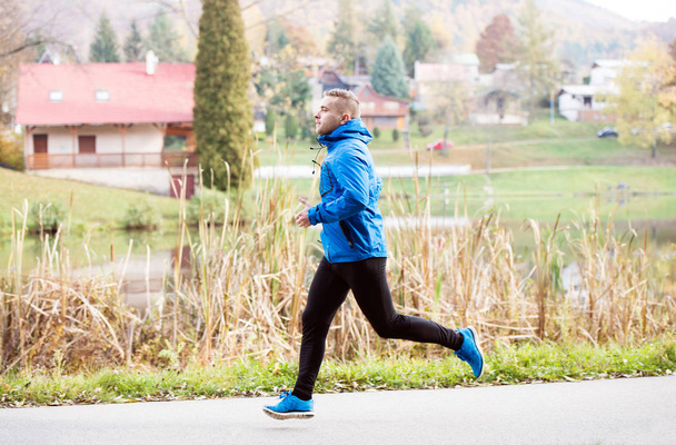Athlete at the lake running against colorful autumn nature - Photo, Image