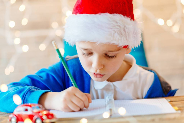 Lapsi kirjoittaa kirjeen joulupukille kotona
. - Valokuva, kuva