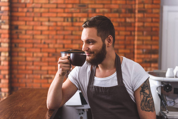 Happy man enjoying latte in coffeehouse - Фото, изображение