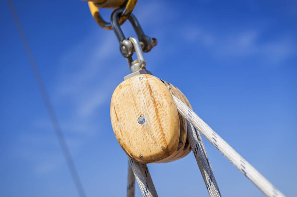 Wooden pulley with ropes under the blue clear sky - Foto, afbeelding