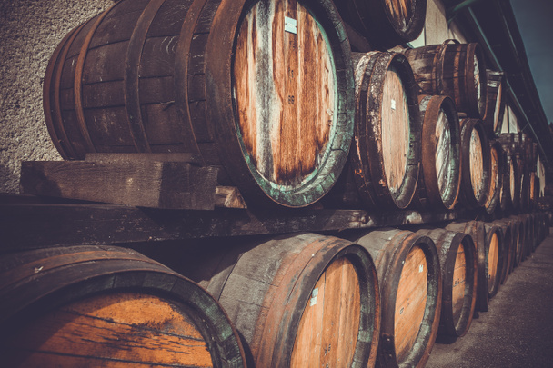 wooden barrels in the distillery folded in the yard in shelves - Photo, Image