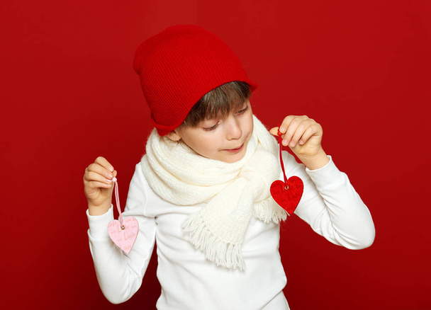 girl child portrait with hearts on red, winter holiday concept - Photo, Image