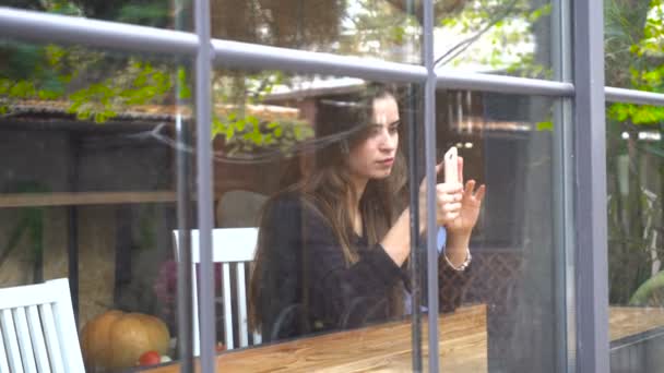 girl sitting near the window and looking at the phone - Filmmaterial, Video