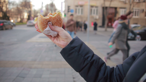 Mujer joven comiendo comida rápida al aire libre
 - Metraje, vídeo