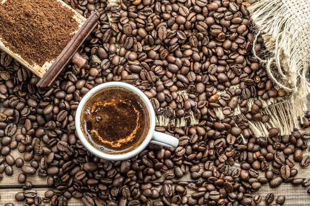 Cup of coffee on roasted beans background, overhead - Фото, зображення