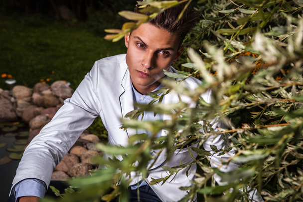 Portrait of young beautiful fashionable man against autumn garden. - Foto, afbeelding