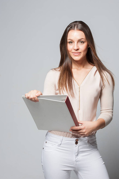 Portrait of smiling young business woman holding a folder - Foto, imagen