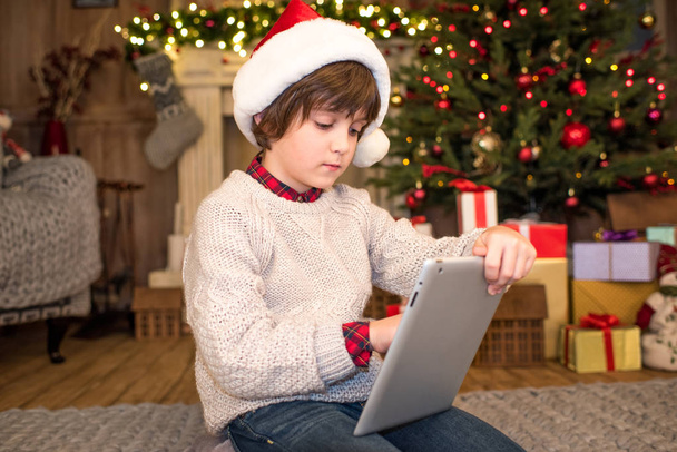 Niño en Santa sombrero usando tableta digital
 - Foto, Imagen