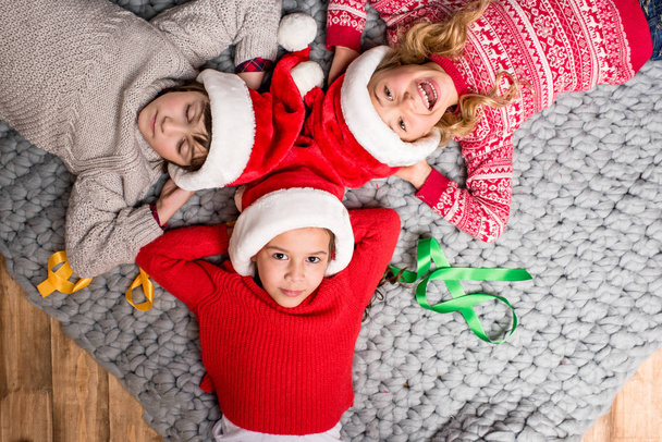 kids in Santa hats lying in circle - Foto, imagen