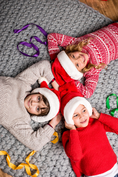 kids in Santa hats lying in circle - Foto, afbeelding