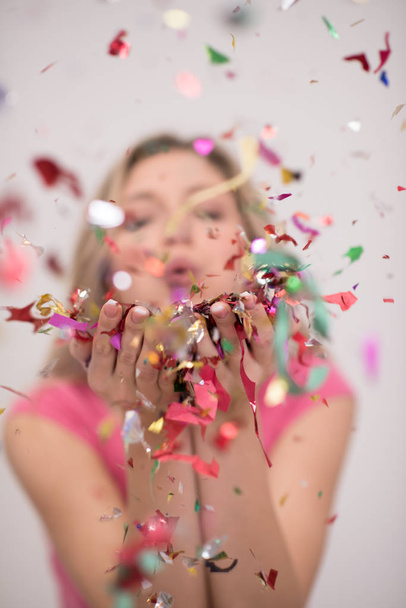 Beautiful  woman blowing confetti in the air party new years eve celebration isolated on white background - Fotó, kép