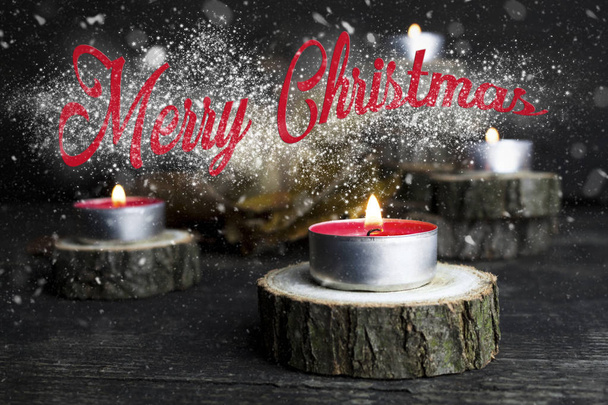 Merry Christmas. Christmas candles burning, decoration on wooden logs resting on rustic wooden background with Snow Flakes And Stardust - 写真・画像