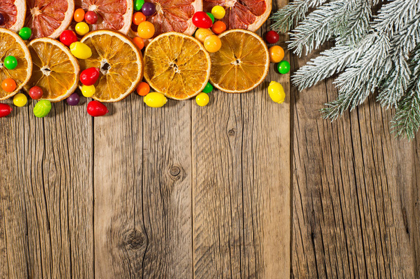 Fir tree branch with orange, grapefruit and candy on an old wood - Photo, image