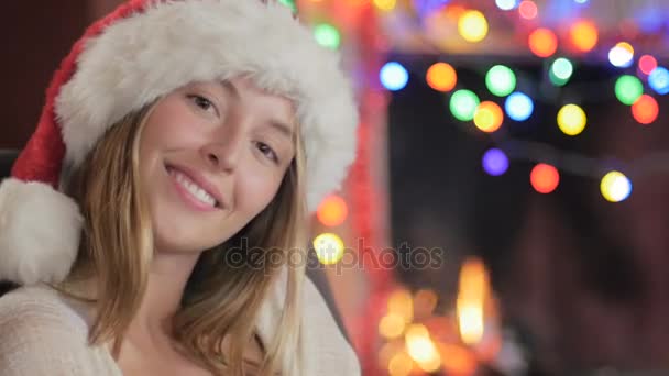 A beautiful young woman in a Santa hat blows a kiss during the holidays - Filmati, video