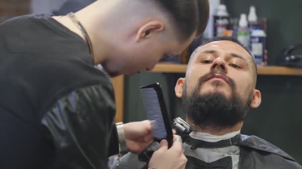 Close-up handsome young bearded man getting beard grooming in modern barbershop. - Filmagem, Vídeo