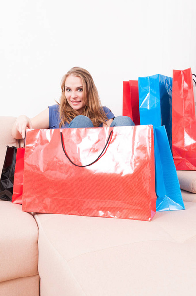 Señora sentada en el sofá encontrando cosas en bolsas de compras
 - Foto, imagen