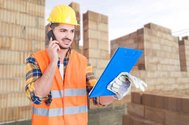Builder worker with clipboard talking on cellphone - Foto, Bild
