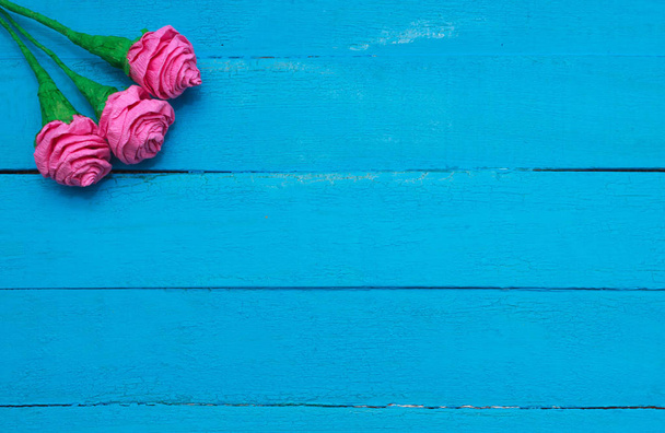 Fresh roses flowers in ray of light on turquoise painted wooden background. Selective focus. Place for text. - Photo, Image