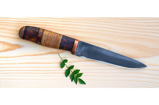 hunting knife with leaf on a wooden surface - Foto, afbeelding