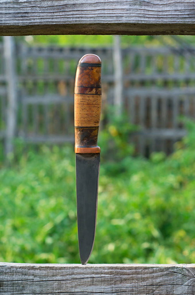 hunting knife with a dark blade stuck in a board - Foto, afbeelding