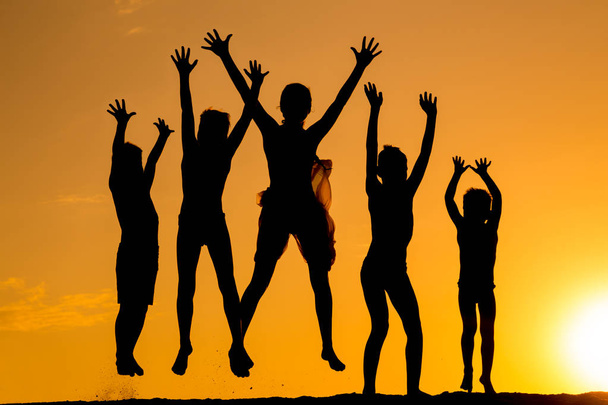 silhouette of five jumping kids against sunset - Valokuva, kuva