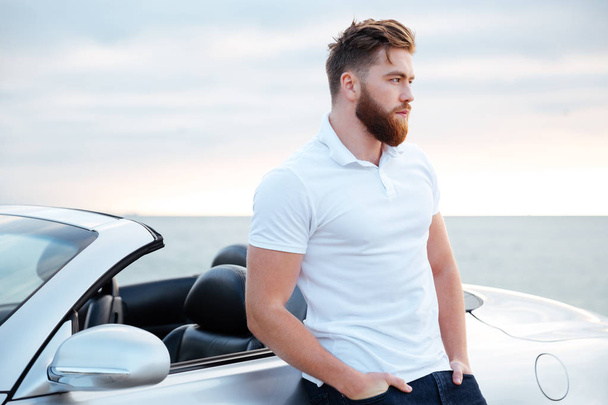Handsome bearded man in white shirt leaning on car outdoors - Foto, immagini