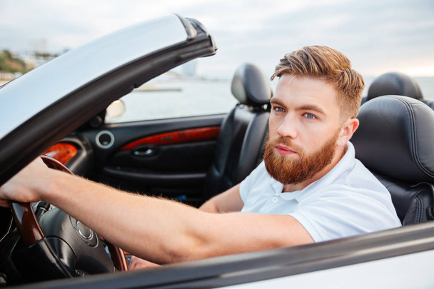 Handsome young man in white shirt driving the car - 写真・画像