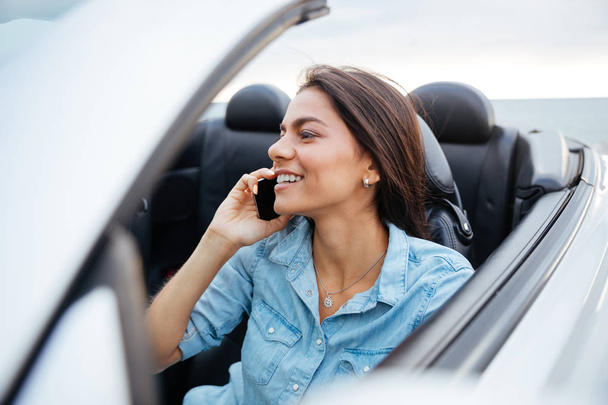 Happy woman driving car and talking on mobile phone - 写真・画像