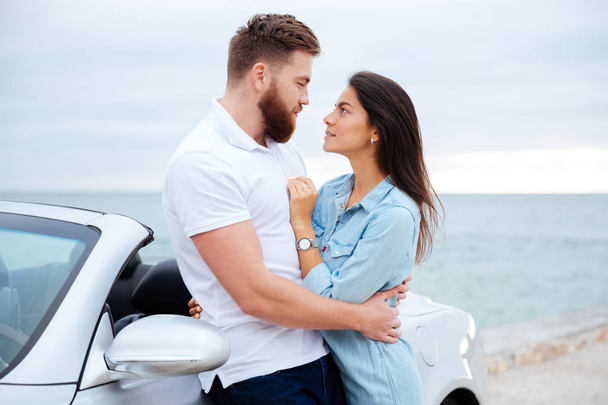 Jeune couple embrasser tout en se tenant près de la voiture au bord de la mer
 - Photo, image