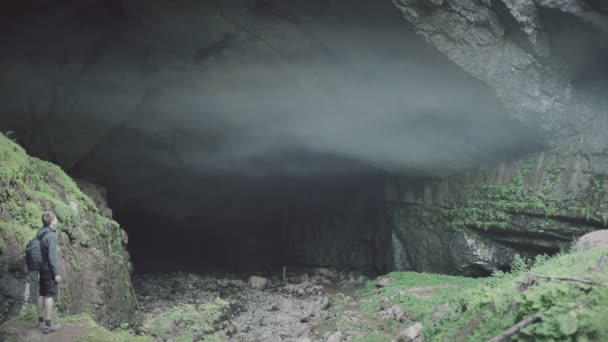 Mann steht im Zeitraffer am Höhleneingang. Magischer Nebel vom Höhleneingang - Filmmaterial, Video