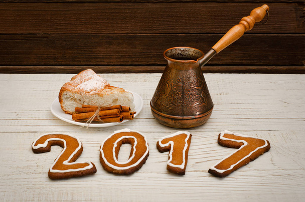 Conceito de Ano Novo. A figura em 2017 de pão de gengibre, panelas e torta de maçã com canela na mesa de madeira
 - Foto, Imagem