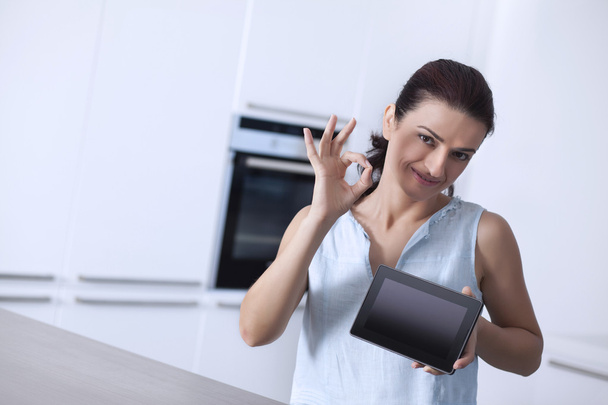 Mujer mostrando una tableta digital y gesto de la mano signo bien
 - Foto, imagen