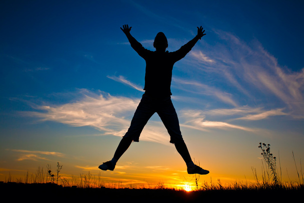 Femme heureuse sautant par-dessus le coucher du soleil ciel bleu
 - Photo, image